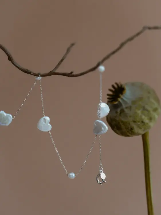 Zbliżenie na Naszyjnik Infinite Pearl w wersji ze srebra próby 925 oraz pozłacanej 24k złotem, z perły okrągłej i perły w kształcie serca, na delikatnym łańcuszku.jpg